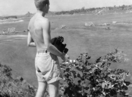 Robert Riese, camera in hand, looks over destroyed railway bridge in Liuzhou, in 1945, during WWII.