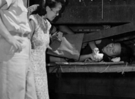 A GI and a local elite pay respects to a refugee at the train station in Liuzhou during WWII, in the fall of 1944, as the Japanese advanced during the Ichigo campaign.