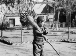 A young candied fruit seller selling candied haws fruit on bamboo skewers during WWII.