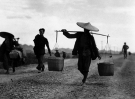 People carrying shoulder poles in China during WWII.