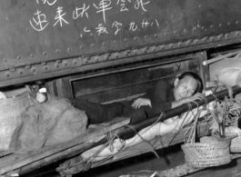 A Chinese refugee stashed away on a precious spot on a train during the evacuation in Guangxi during the fall of 1944. The writing above is a message from someone for another person to meet up on that train car.