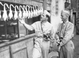 16th Combat Camera Unit photographer Selig Seidler and another man inspect ducks at a restaurant in China during WWII.