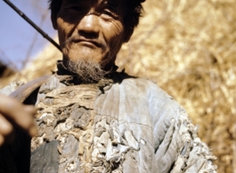 A tattered farmer with a shoulder pole in Yunnan province, China. During WWII.