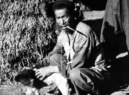 Local people  in China, probably in Yunnan province: A man in rural China with a dog.  From the collection of Wozniak, combat photographer for the 491st Bomb Squadron, in the CBI.