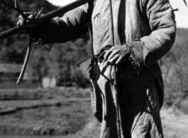 Local people in China, probably in Yunnan province: A farmer shouldering his tools.  From the collection of Wozniak, combat photographer for the 491st Bomb Squadron, in the CBI.