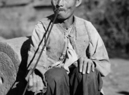 An elderly villager with a long pipe in China, probably in Yunnan province. During WWII.