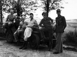 Americans and Chinese socialize while lounging on jeeps, in the CBI.
