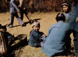 An infant with a colorful hat sitting.  At a rural village near the American base at Yangkai, Yunnan province, in the CBI.