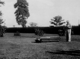 5529-116 A funeral in the CBI. Someone reads over a coffin with an American flag draped over its top, resting on a lawn somewhere in the CBI.