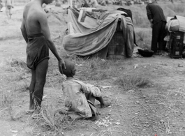 A gravely ill boy is supported by an adult: The sick and weakened during the Chinese civilian evacuation in Liuzhou city Guangxi province, China, during WWII, during the summer or fall of 1944 as the Japanese swept through as part of the large Ichigo push.