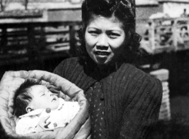 An urban Chinese woman holds a baby during WWII. Local people in Yunnan province, China.