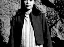 A woman in a maternity dress in a village in Yunnan during WWII. She is likely to be wife of a Nationalist officer, billeted to live in the village, rather than a woman who grew up in the village.