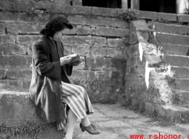 A woman in a maternity dress in a village in Yunnan during WWII. She is likely to be wife of a Nationalist officer, billeted to live in the village, rather than a woman who grew up in the village.