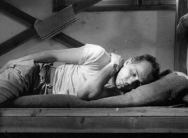 Barracks life at an American base in southwest China during WWII: GI lies pensively on his bunk. 