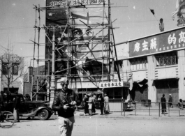 A GI walks on a Kunming street with slogans about Chiang Kai-shek in the background, and an image of British politician Clement Richard Attlee.