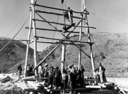 A pole driver, built on-site, is employed by workers in SW China to drive bridge supports into the ground. During WWII.