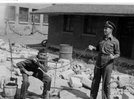 A GI tries out a carrying pole with two buckets in China during WWII.