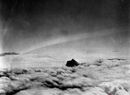 A mountain pokes through the clouds during a war time flight of US planes.