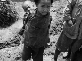 A child bearing a baby on her (most likely) back, during WWII, in Yunnan, China.