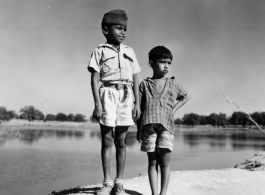 Two boys pose side by side, one in a scout uniform or similar.  Scenes in India witnessed by American GIs during WWII. For many Americans of that era, with their limited experience traveling, the everyday sights and sounds overseas were new, intriguing, and photo worthy.