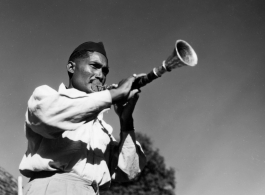 Man blowing horn.  Scenes in India witnessed by American GIs during WWII. For many Americans of that era, with their limited experience traveling, the everyday sights and sounds overseas were new, intriguing, and photo worthy.