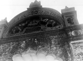 Ornate carved arch doorway, likely as part of a temple complex.  Scenes in India witnessed by American GIs during WWII. For many Americans of that era, with their limited experience traveling, the everyday sights and sounds overseas were new, intriguing, and photo worthy.