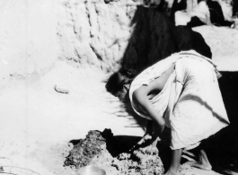 Woman mixing mud or dung and mud with water.  Scenes in India witnessed by American GIs during WWII. For many Americans of that era, with their limited experience traveling, the everyday sights and sounds overseas were new, intriguing, and photo worthy.