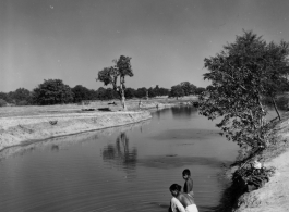 Woman washing cloth in river or canal.  Scenes in India witnessed by American GIs during WWII. For many Americans of that era, with their limited experience traveling, the everyday sights and sounds overseas were new, intriguing, and photo worthy.