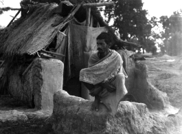 Man squatting on mud wall.  Scenes in India witnessed by American GIs during WWII. For many Americans of that era, with their limited experience traveling, the everyday sights and sounds overseas were new, intriguing, and photo worthy.