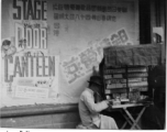 Cigarette vendor in China, set up in front of move advertisement for "Stage Door Canteen" (1943).  Photo from Jesse D. Newman.