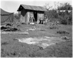 Local people in China: Men prepare to cook rice in a small shack next to American GI tents.  From the collection of Eugene T. Wozniak.