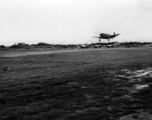 A P-51 fighter plane lands in front of a row of other P-51s in the CBI.