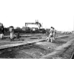 Local people in a train yard in India during WWII. Notice the first aid trucks on flat cars in the background.  From the collection of Eugene T. Wozniak.