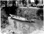 A man poles a small boat on a canal in Kunming, Yunnan province.  From the collection of Eugene T. Wozniak.