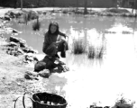 Local people in Yunnan province, China: A woman washes cloth in a village pond. During WWII.  From the collection of Eugene T. Wozniak.