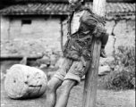 An impoverished possible criminal or suspect tied to a post in WWII China, as a form of punishment.
