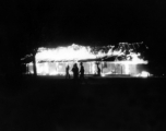 A building on fire at an American base, China, during WWII. Most likely during the retreat in the face of Ichigo in 1944.