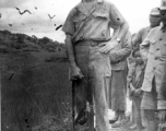 Elmer Bukey poses for a photo with some Chinese friends and a Thompson submachine gun, standing by a rice paddy, at Liangshan China, during WWII.