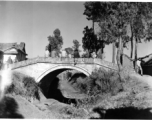 Chinese civilians and Nationalist soldiers pass the time on a small bridge in Yunnan, China, probably near Kunming or Yangkai base. During WWII.  From the collection of Hal Geer.