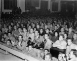 An eager audience of Chinese and American military personnel, along with Chinese civilians, view a performance in China during WWII. 