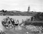 In this fascinating photo--a virtual Norman Rockwell still-life of wartime life in China--Chinese troops, American troops, and Chinese civilians cross the Xiao river (潇水) via ferry near Lingling, China, during WWII. In the background, on the east bank of the river, is the Huilong Pagoda (零陵回龙塔), which remarkably still survives, and has been restored.