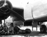 Jim, Frank Bates, Alex, Jim, 1943, in the shade under a B-25. Note large bombs on ground near them.