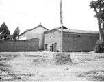 Some large, possibly official, buildings near or on an American air base in Yunnan, China, during WWII. Note the small guard shack at the opening between the structures.