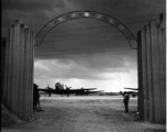 Guarded gates of the Nationalist Kunming Air Force Officer Training School during WWII, with C-46 transports, and a fuel trailer (on the far right).