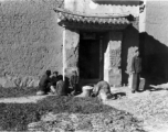 Local people in Yunnan province, China, chatting, sorting pea pods, or waiting as greens dry in the sun. During WWII.