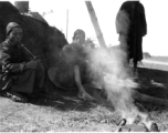 Local people in China: Men smoke and rest in the shade while their food heats over a tiny fire.