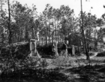 GI explorations of the hostel area at Yangkai air base during WWII: A GI walks past graves next to hostel buildings.