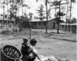 GI explorations of the hostel area at Yangkai air base during WWII: A woman carrying an infant works.