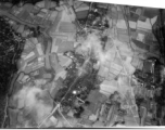 Bombs explode on a compact village in the midst of rice paddies in either SW China (esp. Guangxi), or Burma, or French Indochina during WWII. The bright white spot is the arc flash of a bomb explosion, caught exactly at the right time.