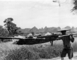 Men shoulder stretcher with injured or sick person in Guangxi, China, during WWII.